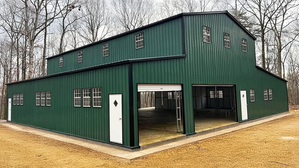 Two-story green metal barn with windows and drive-through bays