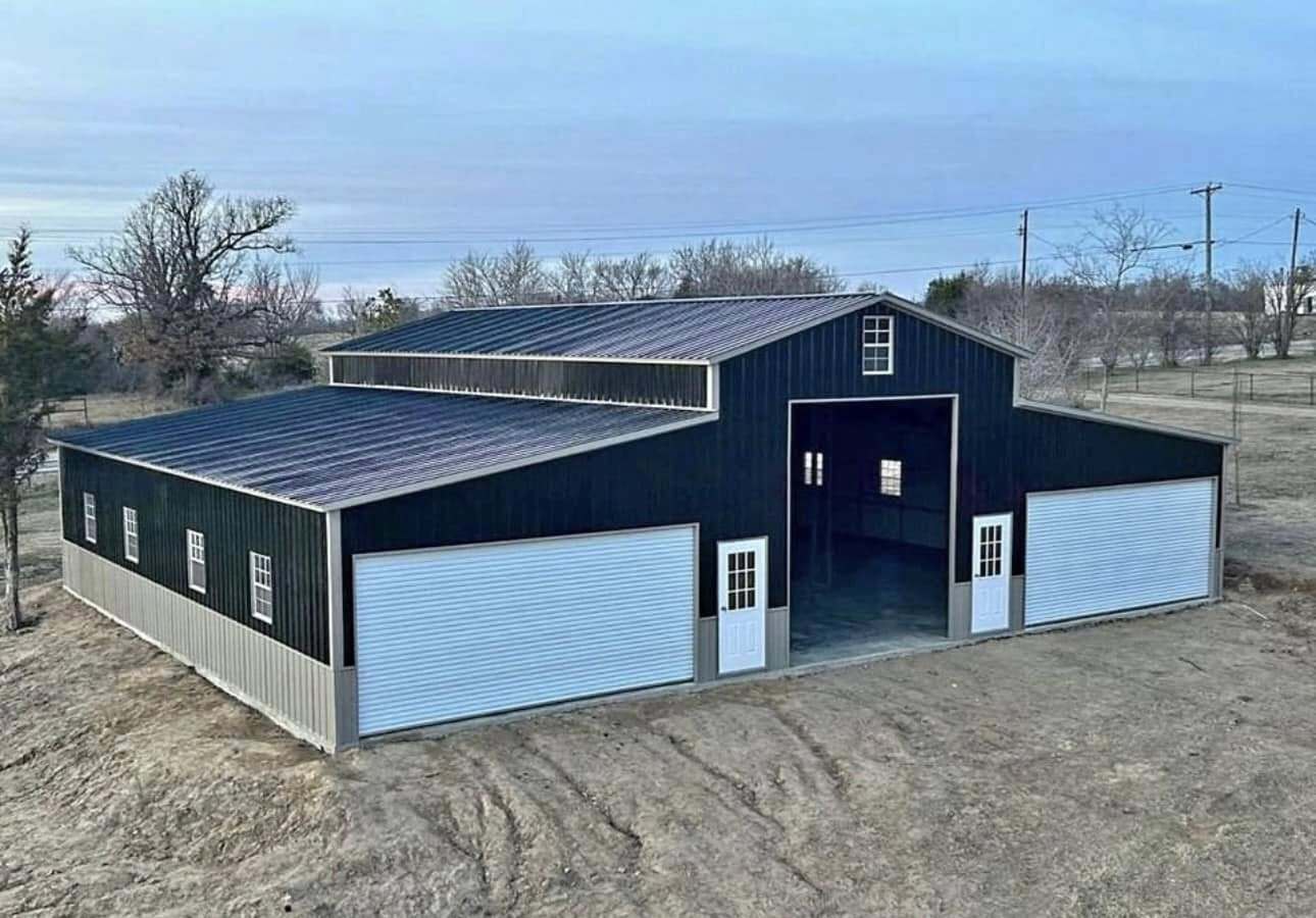 Navy metal barn with center drive-through bay and white roll-up doors