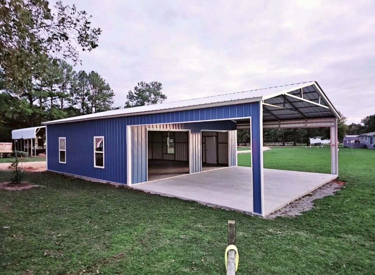 Blue metal building with open carport cover and concrete pad
