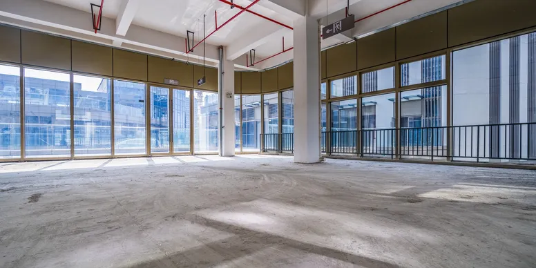 Open-plan commercial steel building interior with floor-to-ceiling glass and concrete floor